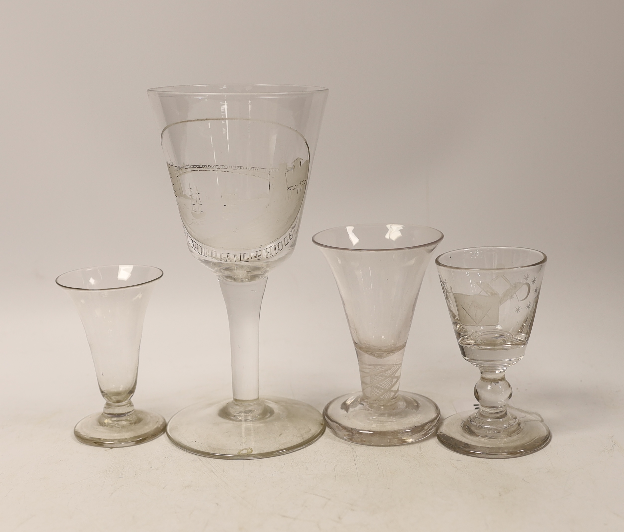 Four late 18th century drinking glasses; a DSOT stem toast masters glass, one with wheel engraved Masonic symbols, and a large wheel engraved goblet decorated with a view of Sunderland bridge, 20cm high